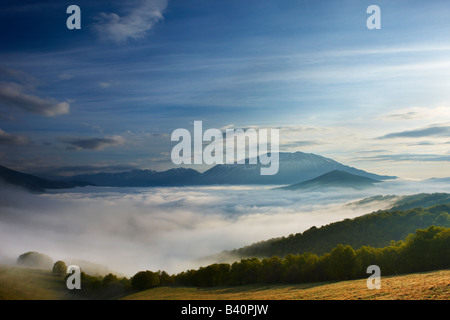 mist lying on the Piano Grande at dawn with the mountains of Monti Sibillini National Park rising above, Umbria, Italy Stock Photo