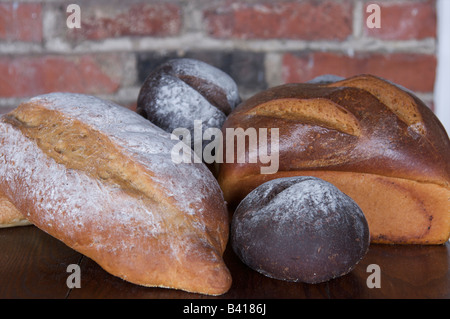 Pumpernickel, sourdough and other hard breads displayed in front of a brick wall. Stock Photo