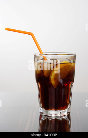 Drinking glass filled with kola, ice cubes, a lemon slide and a straw Stock Photo