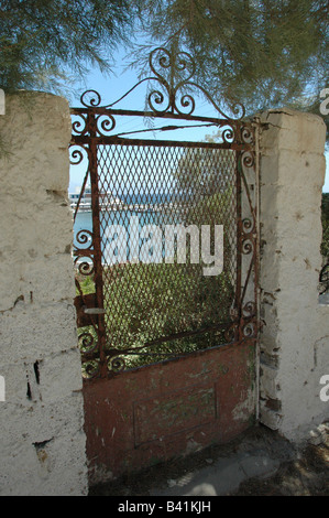 Old rusty gate, with the view of Pisso Livadi beach in the background. Paros. Greece. Stock Photo