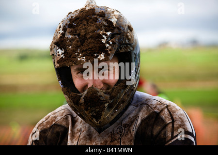 man with crash helmet covered in dirt involved in motocross racing having removed his face visor Stock Photo