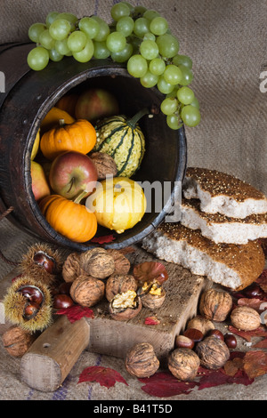 Antique wooden bucket filled with autumn products and traditional bread on a wooden board Stock Photo
