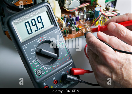 A digital multimeter being used to check resistance on a circuit board Stock Photo