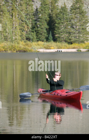 A sea kayaker fly fishing in an alpine lake high up in the san juan mountains near telluride, colorado at sunset in the fall Stock Photo