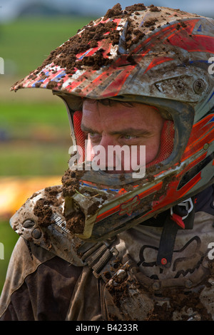 man with crash helmet involved in motocross racing with his helmet and clothing covered in mud Stock Photo