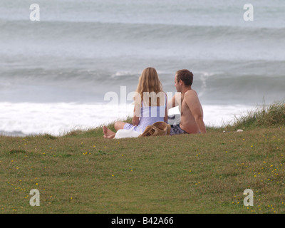 Couple sat on the cliff top looking out to sea Stock Photo