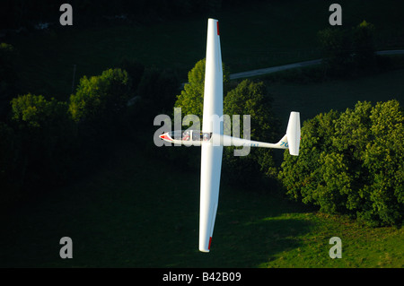 A trainer glider Grob Twin Astir fliying over Alps forest in the evening light - France Stock Photo