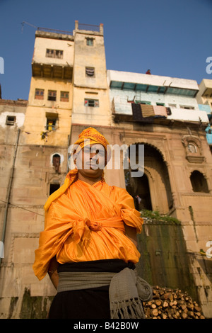 A young sadhu stands in front of one of the riverside temples in the city of Varanasi, India. He wears orange. Stock Photo