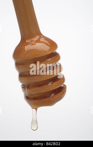 Wooden honey server with dripping honey close up Stock Photo