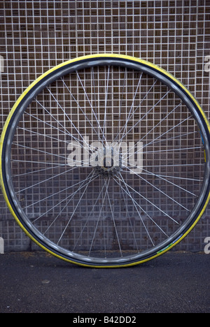 close up of defunct racing bike wheel leaning against tiled wall Stock Photo