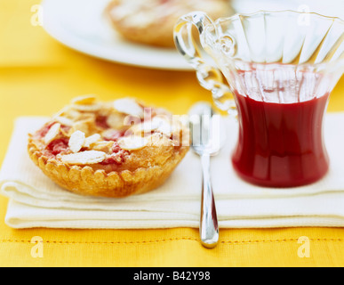 Almond,pink praline and banana tartlet with summer fruit coulis Stock Photo