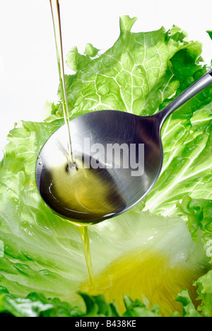 Pouring a drop of olive oil onto a lettuce leaf Stock Photo