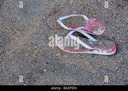 pair of pink flip flops left on the beach Stock Photo