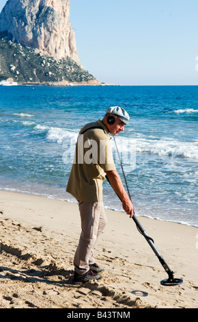 A man searches for treasure on the beach with a metal detector Stock ...