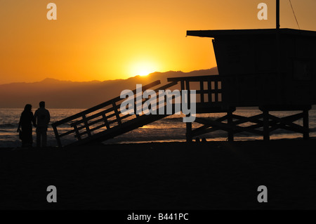 A couple's romantic evening is concluded with a sunset stroll on the beach, as they strool by one of LA's lifeguard towers. Stock Photo