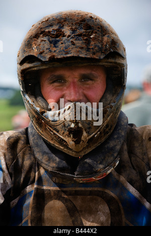 Man with crash helmet covered with mud involved in motocross racing, circuit near Darvel Ayrshire Scotland Stock Photo