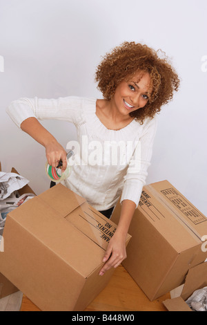 African woman taping moving box Stock Photo