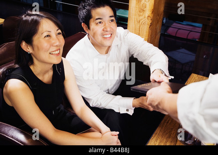 Asian couple paying restaurant bill Stock Photo