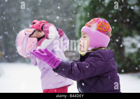 Asian sisters playing in snow Stock Photo