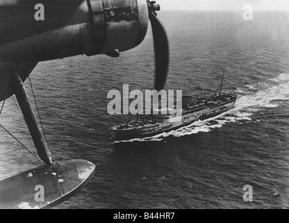 A Royal Air Force Coastal Command Sunderland flying boat flying over a transport ship while on a convoy protection patrol Stock Photo