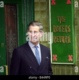 Prince Charles shelters from the rain in the doorway of the Rovers Return pub on the set of the soap Coronation Street Stock Photo