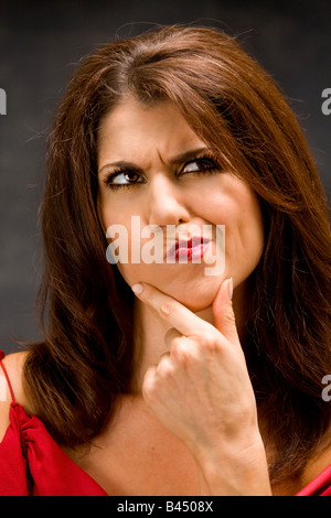 The beautiful face of a thinking woman with hand on chin Stock Photo