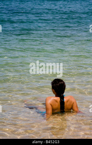 Panama, Isla Grande, A young woman enjoys the view while she tans sitting on the sand taken a bath by the crystalline waters Stock Photo