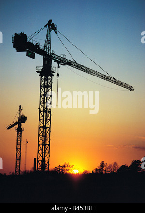 Silhouette of construction site cranes against sunset Stock Photo