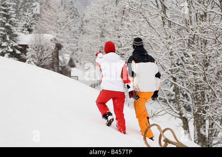 Austria, Salzburger Land, Altenmarkt-Zauchensee, Young couple pulling sledge, rear view Stock Photo