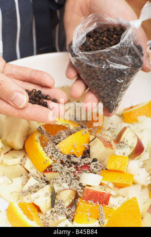 Person flavouring the stuffing with peppercorns, close-up Stock Photo