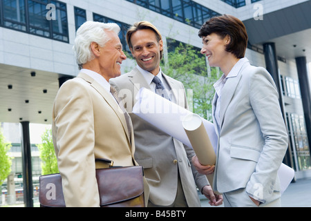 Germany, Baden Württemberg, Stuttgart, Two business men, woman holding wrapped up blueprint Stock Photo