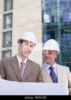 Germany, Baden-Württemberg, Stuttgart, two businessmen with hard hats discussing building plan Stock Photo