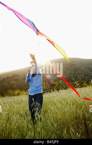 Asian woman flying kite in field Stock Photo