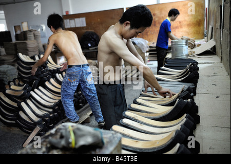 Laborers spray glue for office chairs at a Taiwan capital furniture factory in Huizhou Guangdong China. 21 Sep 2008 Stock Photo