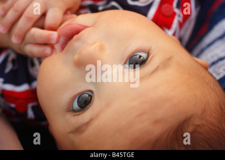 Six month old baby boy chewing on fingers looking up from stroller.  Baby is half Asian and half Caucasian. Stock Photo