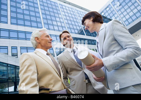 Germany, Baden Württemberg, Stuttgart, Two business men, woman holding wrapped up blueprint Stock Photo