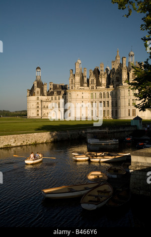 Tourists in a rowing boats on the River Cosson looking southeast towards the northern façade of Chateau de Chambord at sunset
