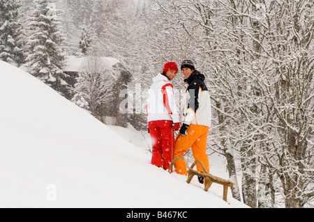 Austria, Salzburger Land, Altenmarkt-Zauchensee, Young couple pulling sledge Stock Photo