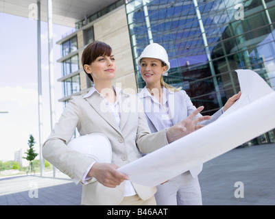 Germany, Baden-Württemberg, Stuttgart, Two businesswomen with hard hats discussing building plan Stock Photo