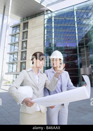 Germany, Baden-Württemberg, Stuttgart, two businesswomen with hard hats discussing building plan Stock Photo