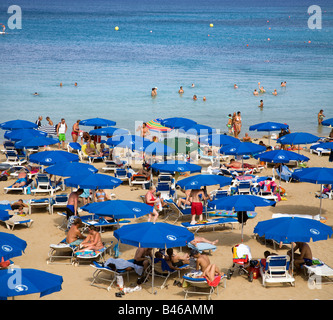 VIEW OF FIG TREE BAY, PROTARAS, IN CYPRUS WITH MANY BLUE UMBRELLAS AND GOLDEN SAND Stock Photo