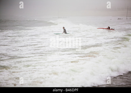 Surfing waves of Far Rockaway Beach during very foggy day New York USA Stock Photo