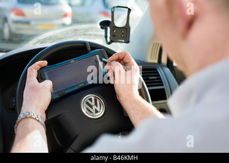 Mobile engineer using a small psion pda portable computer in his van cabin to check itinerary with his office and keep in touch Stock Photo