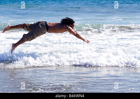 Young African American male caught in the air as he is diving into the water at County Line State Beach in Malibu California Stock Photo