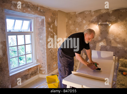 Man decorating room in old country cottage UK Stock Photo