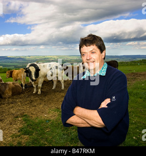 English farmer standing in field with his herd of cows on a diary farm UK Stock Photo