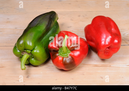 Three freshly picked home grown organic sweet peppers on rustic kitchen table UK September Stock Photo