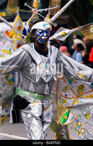 London , Notting Hill Carnival parade , handsome young black man with painted face & silver butterfly costume dancing in pageant Stock Photo