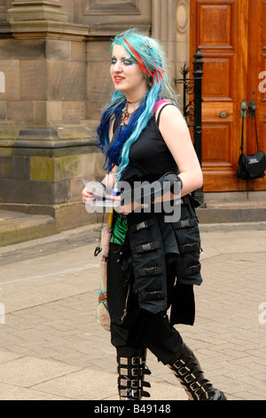 Edinburgh Fringe Festival punk girl in black , long blue and red hair , body piercing & buckled boots with fly sheets for shows Stock Photo