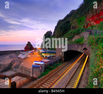 Sunrise from the railway footbridge at Dawlish in South Devon with the light trails of a train coming out of the tunnel Stock Photo